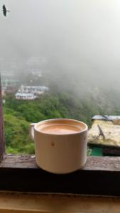 a cup of coffee sitting on a window sill at Goroomgo Shah Guest House Nainital - Excellent Customer Service in Nainital