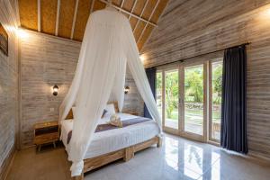 a bedroom with a bed with a mosquito net at Le Biu garden View in Nusa Lembongan