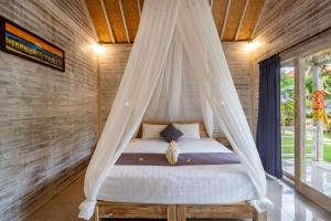 a bed with a mosquito net in a room at Le Biu garden View in Nusa Lembongan