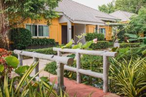 a yellow house with a fence in front of it at Eastiny Resort & Spa in Nong Prue