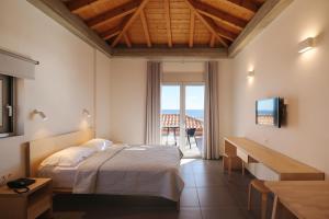 um quarto com uma cama, uma televisão e uma varanda em Pasithea Suites em Monemvasia