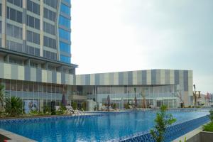 uma piscina em frente a um edifício em HARRIS Hotel & Convention Cibinong City Mall Bogor em Bogor