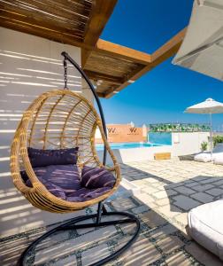 a hanging chair on a patio with a pool at White Swan in Rethymno