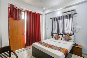 1 dormitorio con cama y cortina roja en FabExpress Samira Residency, Near Botanical Garden, en Noida