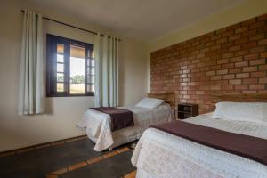 a bedroom with two beds and a brick wall at Apartamento na Fazenda c/ Piscina Termica in Palmeira