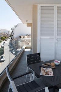 uma mesa e cadeiras numa varanda com vista para uma rua em StayMela Apartments - Kappara em Taʼ Kappara