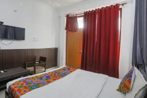 1 dormitorio con cama y cortina roja en FabExpress Samira Residency, Near Botanical Garden, en Noida