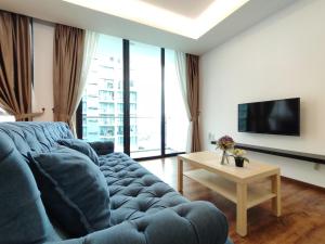 ein Wohnzimmer mit einem blauen Sofa und einem TV in der Unterkunft viva3@onehomestay, 3 Rooms in Kuching