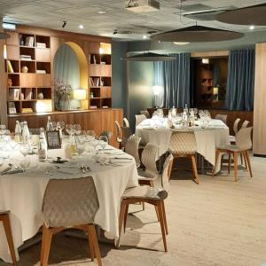 une salle à manger avec des tables et des chaises blanches dans l'établissement Relais Saint Jacques - Châteauroux, à Déols