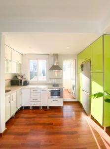 een keuken met witte en groene kasten en houten vloeren bij Penthouse Oceaview Apartment in Cala del Moral