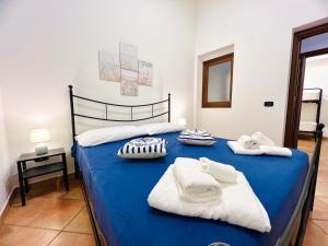 a bedroom with a blue bed with towels on it at Casa Carlotta Apartments in Terrasini