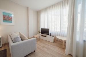 uma sala de estar com um sofá branco e uma televisão em Trindade Deluxe by Hosty no Porto
