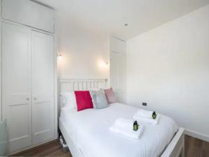 1 dormitorio blanco con 1 cama blanca grande con almohadas rosas en Stylish Flat Centrally Located I Pass The Keys en Twyford