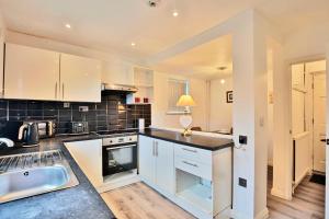 a kitchen with white cabinets and a black counter top at Butlers Meadow House, Sleeps 5, near Blackpool Tower, BAE System, Free Parking - by NMB Property in Weeton