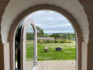 een boog opent naar een uitzicht op een grasveld bij Clotted Cream -Lydcott Glamping, Cornish Sea Views in Looe