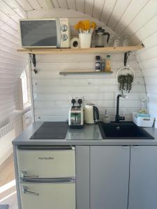 a kitchen with a sink and a microwave at Clotted Cream -Lydcott Glamping, Cornish Sea Views in Looe
