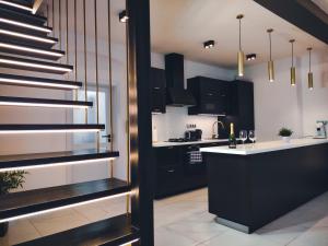 a kitchen with black cabinets and a staircase at Boutique Apartment Owned by Emperor Peter The Great With 2 Balconies & Jacuzzi in Karlovy Vary