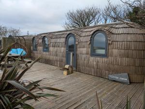 a large building with windows on a wooden deck at Clotted Cream -Lydcott Glamping, Cornish Sea Views in Looe