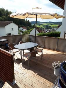 einen Tisch, Stühle und einen Regenschirm auf einer Terrasse in der Unterkunft Heidi`s Ferienhaus in Mittenaar