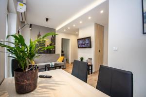 a dining room and living room with a table and a plant at InPoint Aparthotel Grzegórzecka 11 in Kraków