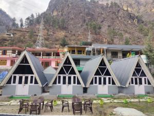a building with tables and chairs in front of it at Giggling Goons Cabins & Kitchen in Kasol