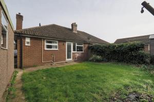 a brick house with a lawn in the yard at 3 Bed Bungalow In Woking in Horsell