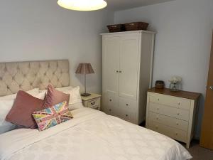 a bedroom with a white bed with pillows and a cabinet at Cheshire East Detached 3BD, Central home CW1 in Crewe