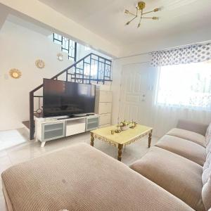 ein Wohnzimmer mit einem TV, einem Sofa und einem Tisch in der Unterkunft 4BEDROOMS Elegant House For Family & Groups Staycation In Cagayan de Oro City in Cagayan de Oro