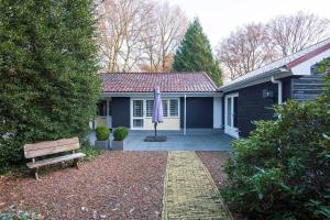 a house with a bench and an umbrella in the yard at Klein Doornroosje (gelegen op Doornroosje landgoed) in Ermelo