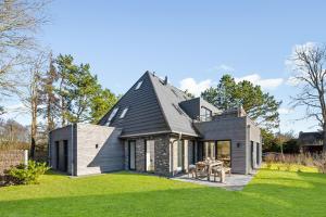 a house with a black roof on a green lawn at Flaute in Sankt Peter-Ording