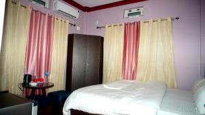 Schlafzimmer mit einem Bett mit rosa und gelben Vorhängen in der Unterkunft Pokhari Cottage Private Limited in Bahāsi