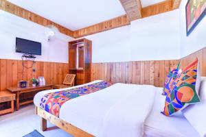 a bedroom with a bed and a desk and a tv at FabHotel Elavali Valley in Manāli