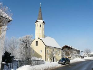 una iglesia cubierta de nieve con un coche aparcado al lado en Kampenwand-Loft, en Aschau im Chiemgau