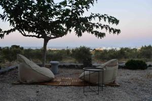duas cadeiras brancas e uma mesa debaixo de uma árvore em Olive Villa em Kamari
