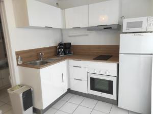 a white kitchen with a sink and a refrigerator at L'Albatros 15 in Fort-Mahon-Plage