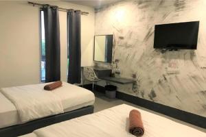 a bedroom with two beds and a tv on a wall at Hotel Ventura in Kangar