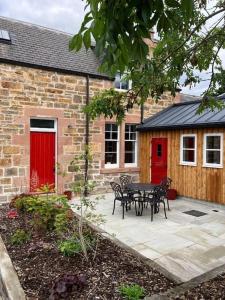 a patio with a table and chairs in front of a building at Signalman's Cottage in Clachnaharry in South Kessock