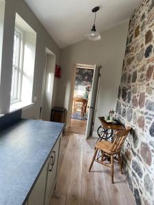 a kitchen with a table and a stone wall at Signalman's Cottage in Clachnaharry in South Kessock