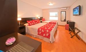 a bedroom with a bed and a desk with a laptop at Hotel Esmeralda Select in Mar del Plata