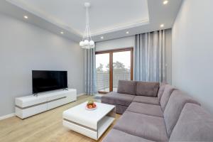 a living room with a couch and a flat screen tv at Porta Mare - Apartment with Sea View Balcony & Parking by Renters in Dziwnówek