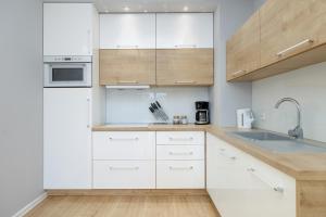 a kitchen with white cabinets and a sink at Porta Mare - Apartment with Sea View Balcony & Parking by Renters in Dziwnówek