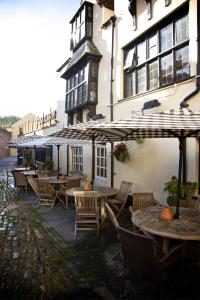 a restaurant with tables and umbrellas in front of a building at The Crown at Wells, Somerset in Wells