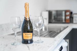 a bottle of wine and two wine glasses on a counter at Stylish Brierley Hill - 1 Bed Apt - Free Parking - Netflix & Wifi - 305O in Brettell Lane
