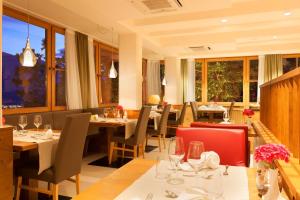 a restaurant with tables and chairs and windows at Hotel Kiendl in Schenna