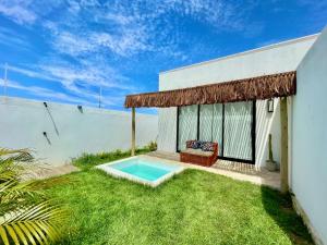 een achtertuin met een zwembad en een huis bij Casa privativa na Vila Ser tão zen #02 in Tibau do Sul