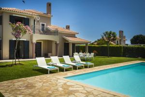 a house with a pool and chairs and a table at Villa Haris in Argostoli