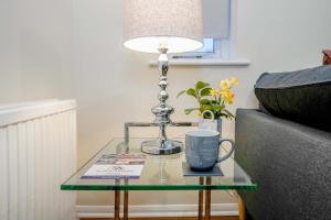 a glass table with a lamp and a mug on it at Lummis Vale in Ipswich
