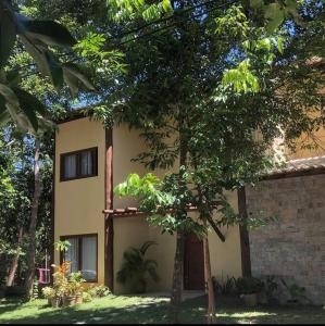 un edificio con un árbol delante de él en Casa 05 suítes, piscina e natureza en Mata de Sao Joao