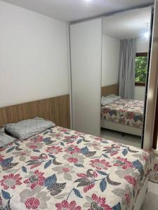 Schlafzimmer mit einem Bett mit Blumendecke und einem Spiegel in der Unterkunft Casa 05 suítes, piscina e natureza in Mata de Sao Joao