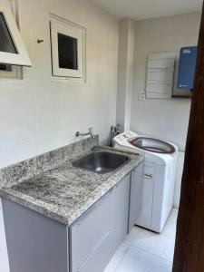 y baño con lavabo y lavadora. en Casa 05 suítes, piscina e natureza en Mata de Sao Joao